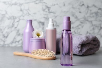 Photo of Different hair products, towel and brush on grey table. Space for text