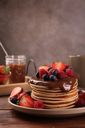 Stack of tasty pancakes with fresh berries and chocolate spread on wooden table, space for text