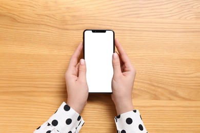 Photo of Woman with smartphone at wooden table, top view