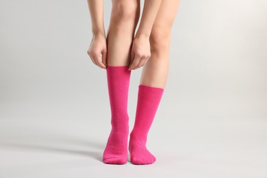 Photo of Woman in stylish bright pink socks on light grey background, closeup