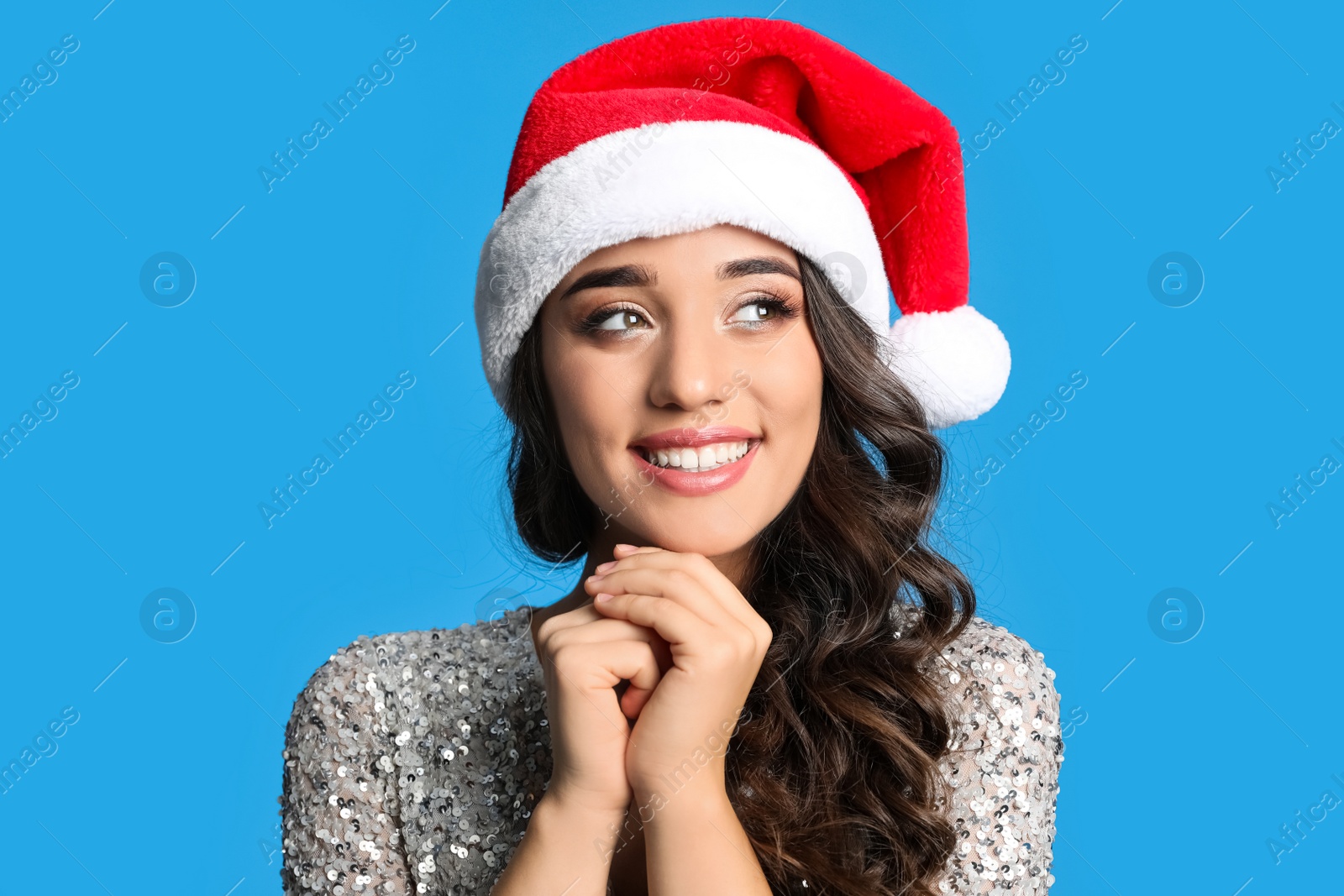 Photo of Beautiful woman in Santa hat on blue background. Christmas party
