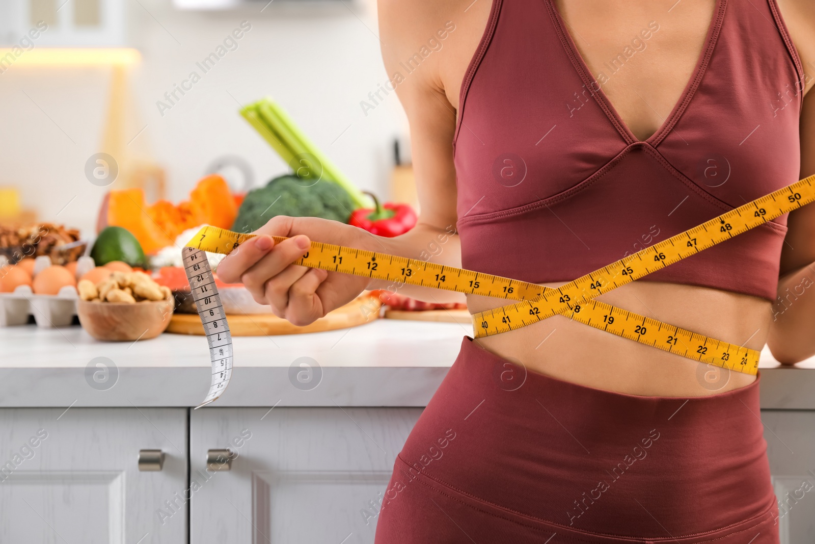 Photo of Woman with measuring tape in kitchen, closeup. Keto diet