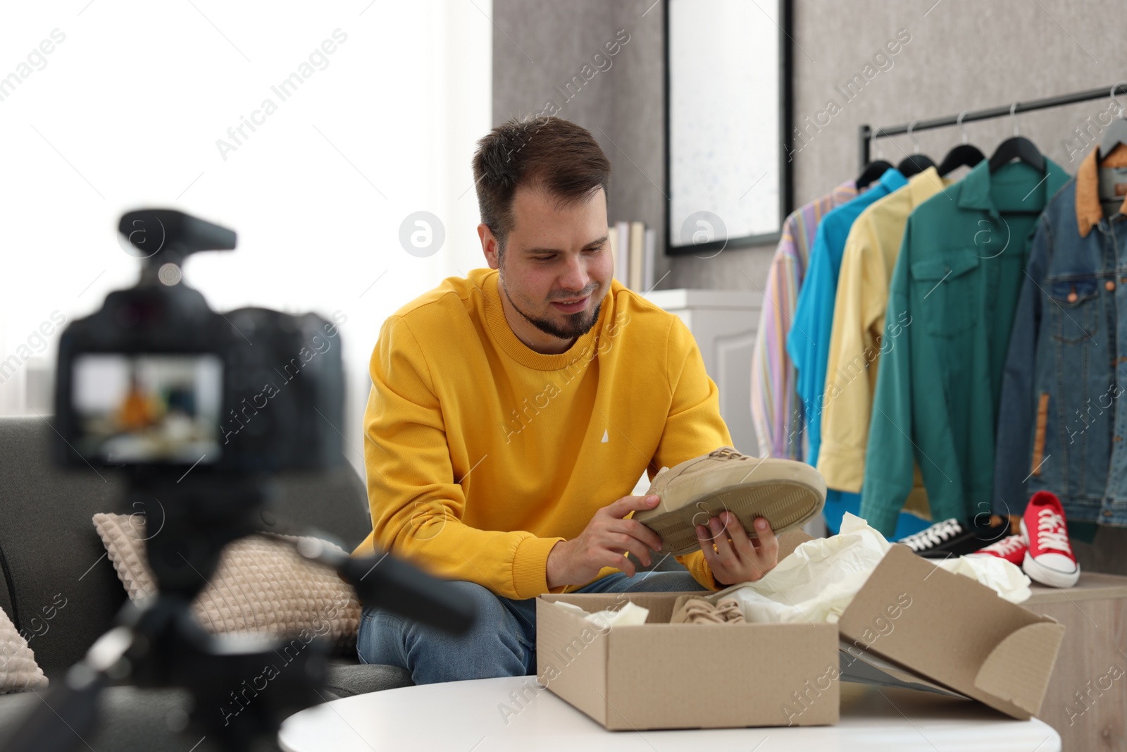 Photo of Smiling fashion blogger looking at shoe while recording video at home