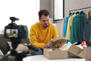 Smiling fashion blogger looking at shoe while recording video at home