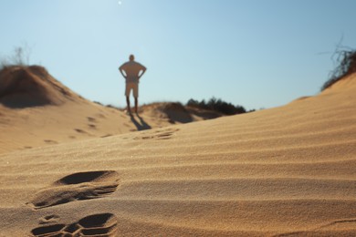 Photo of Man walking through desert, focus on footprint in sand