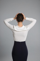 Photo of Young businesswoman in elegant suit on grey background, back view