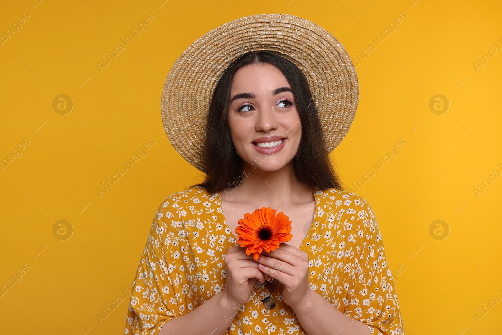 Photo of Beautiful woman with spring flower in hands on yellow background