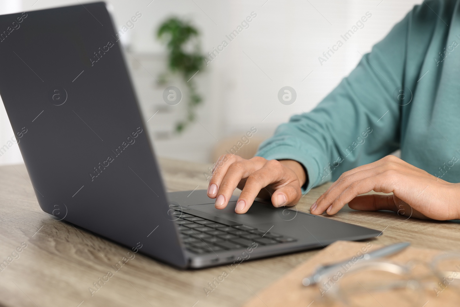 Photo of Woman using laptop at wooden desk indoors, closeup