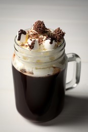 Photo of Mason jar of delicious hot chocolate with whipped cream on white wooden table, closeup