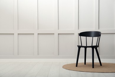 Black wooden chair near white wall indoors. Space for text