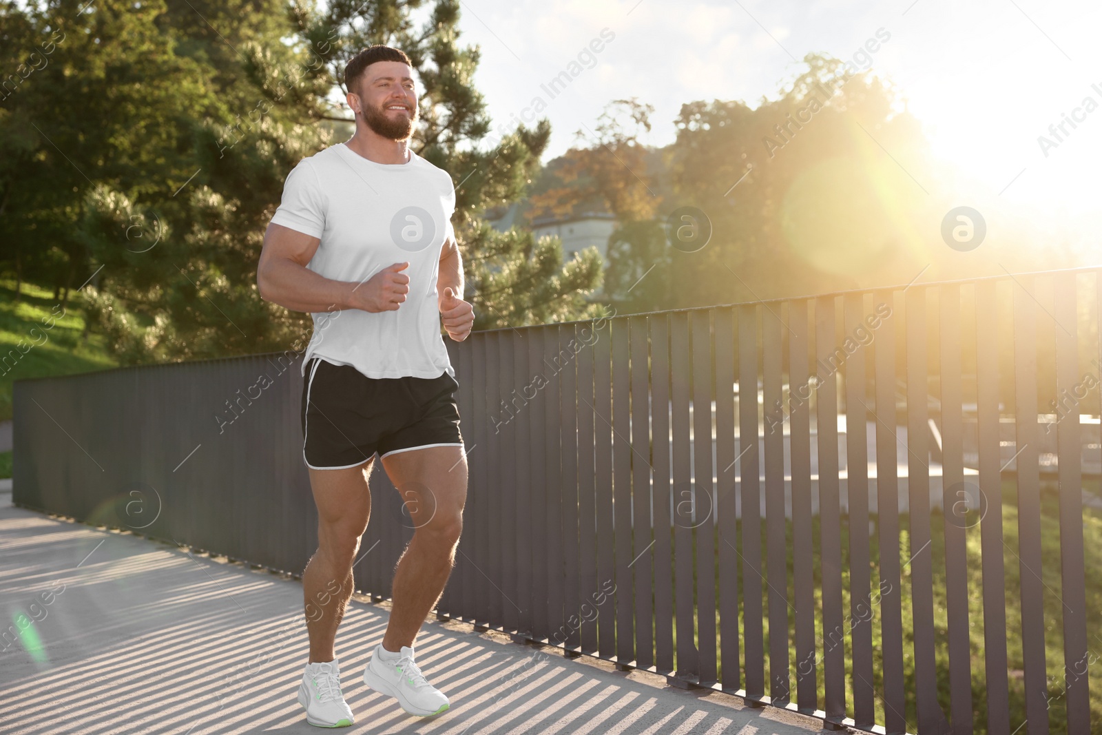 Photo of Young man running outdoors on sunny day. Space for text