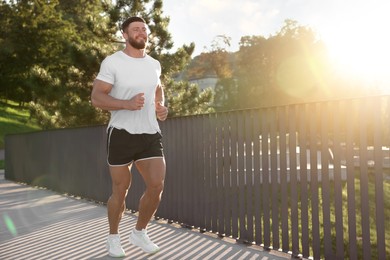 Young man running outdoors on sunny day. Space for text