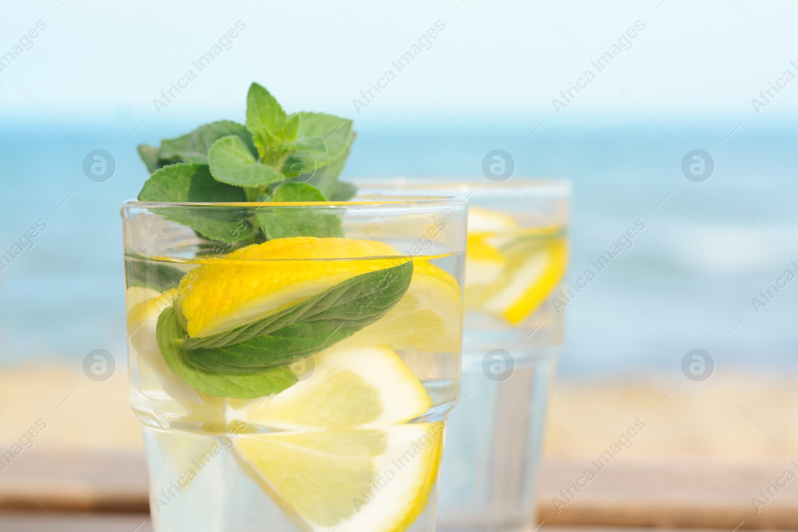 Photo of Refreshing water with lemon and mint on blurred background, closeup