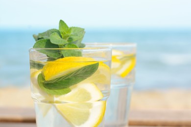 Refreshing water with lemon and mint on blurred background, closeup