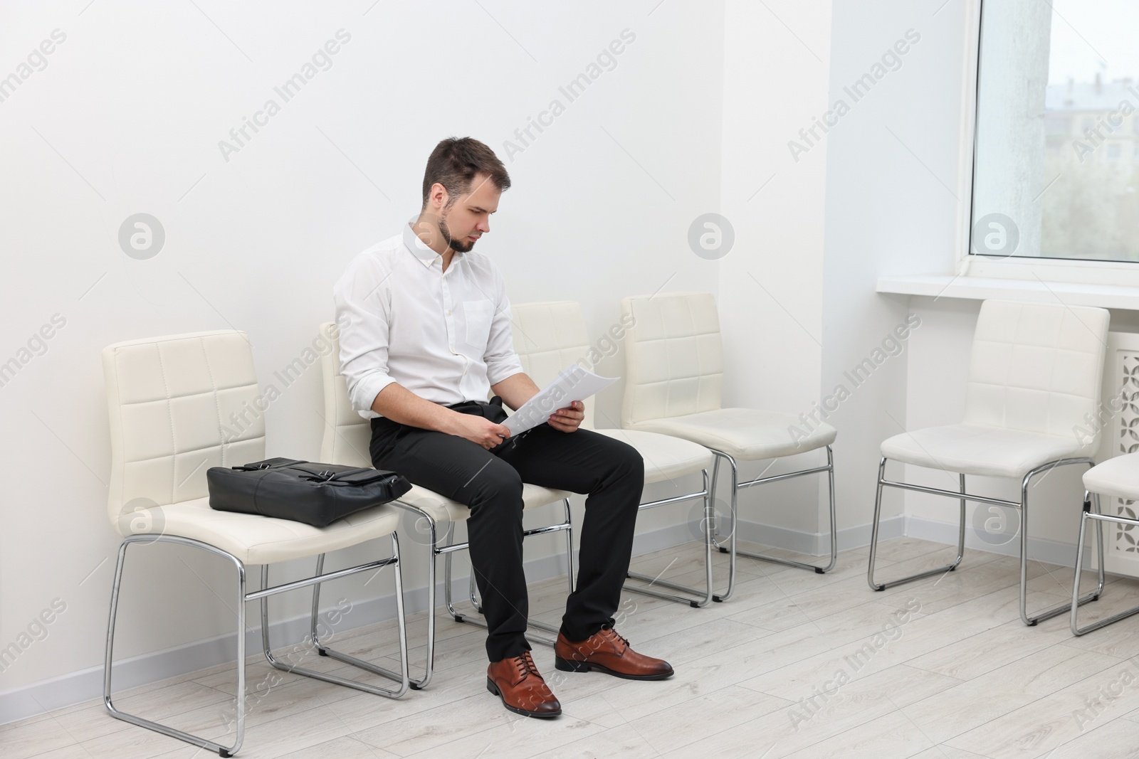 Photo of Man with sheet of paper waiting for job interview indoors