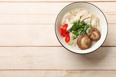 Photo of Delicious ramen with meat and mushrooms in bowl on wooden table, top view. Space for text