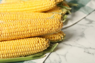 Bunch of corn cobs on white marble table, closeup