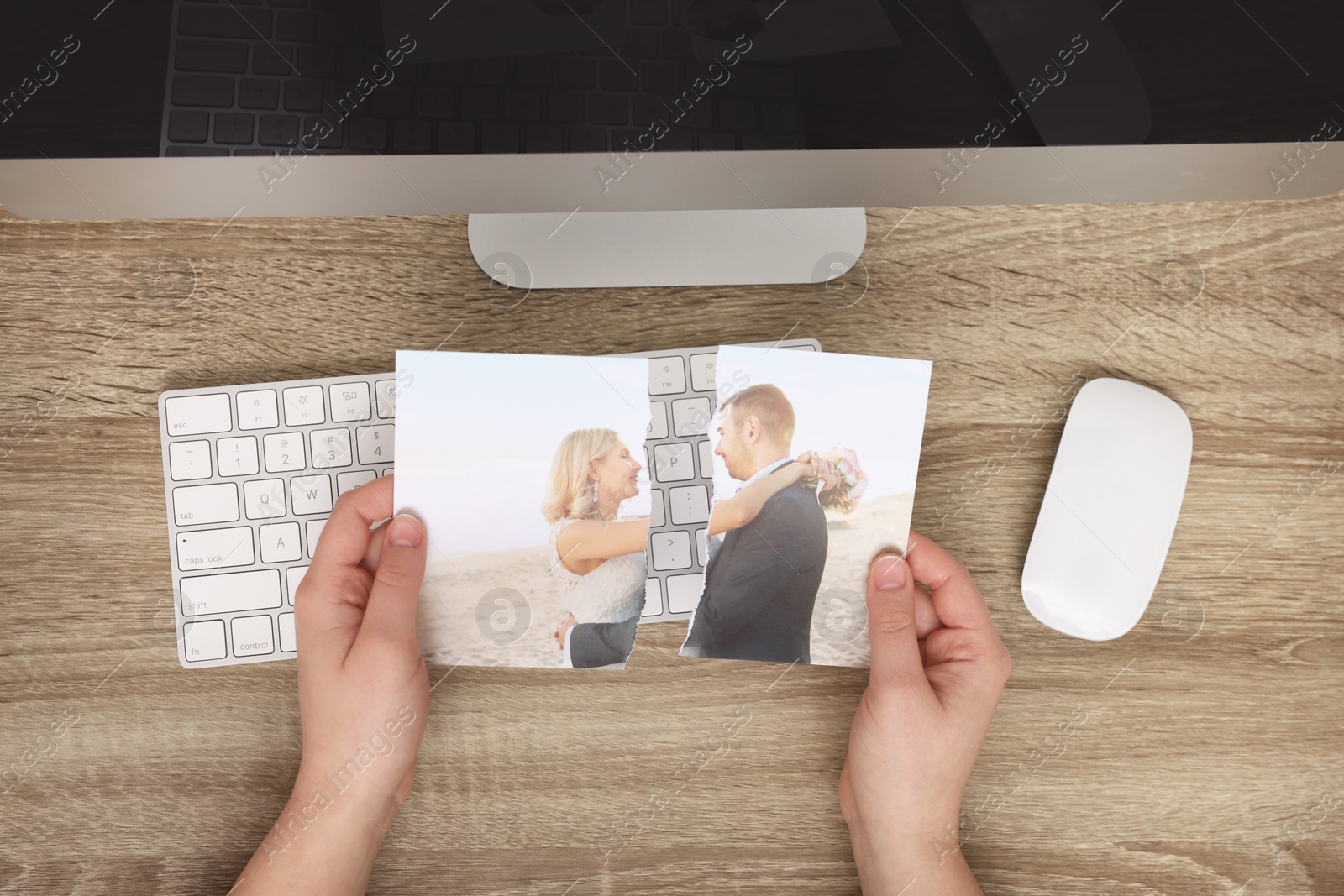 Photo of Woman holding torn photo at wooden table indoors, top view. Divorce concept