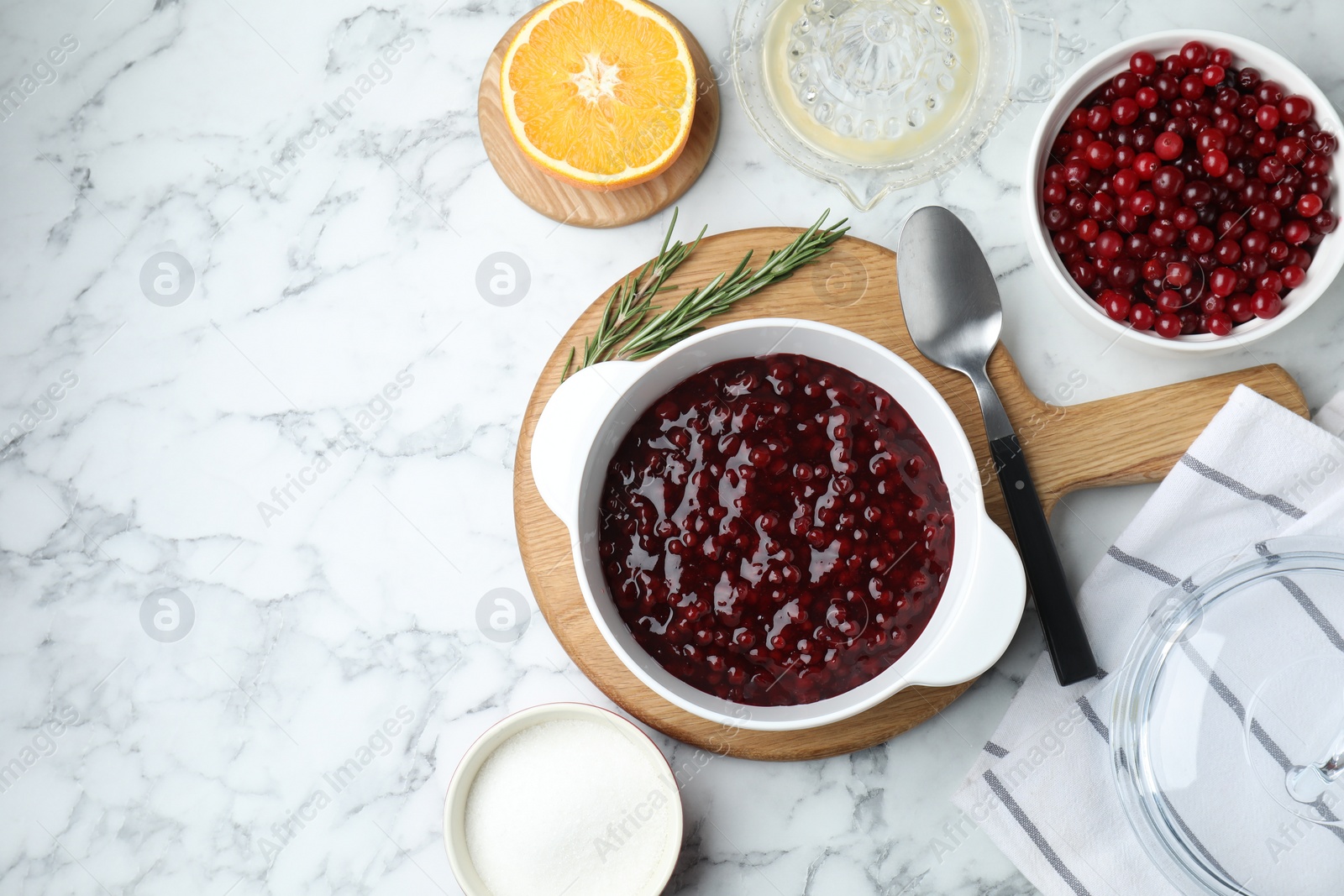 Photo of Fresh cranberry sauce in bowl served on white marble table, flat lay. Space for text