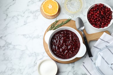 Photo of Fresh cranberry sauce in bowl served on white marble table, flat lay. Space for text