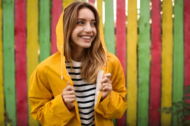 Beautiful young woman in stylish autumn clothes near color fence