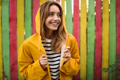 Photo of Beautiful young woman in stylish autumn clothes near color fence