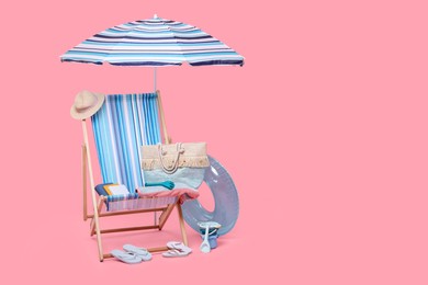 Photo of Deck chair, umbrella and other beach accessories on pink background, space for text. Summer vacation