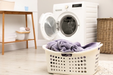 Photo of Basket with laundry and washing machine indoors, space for text