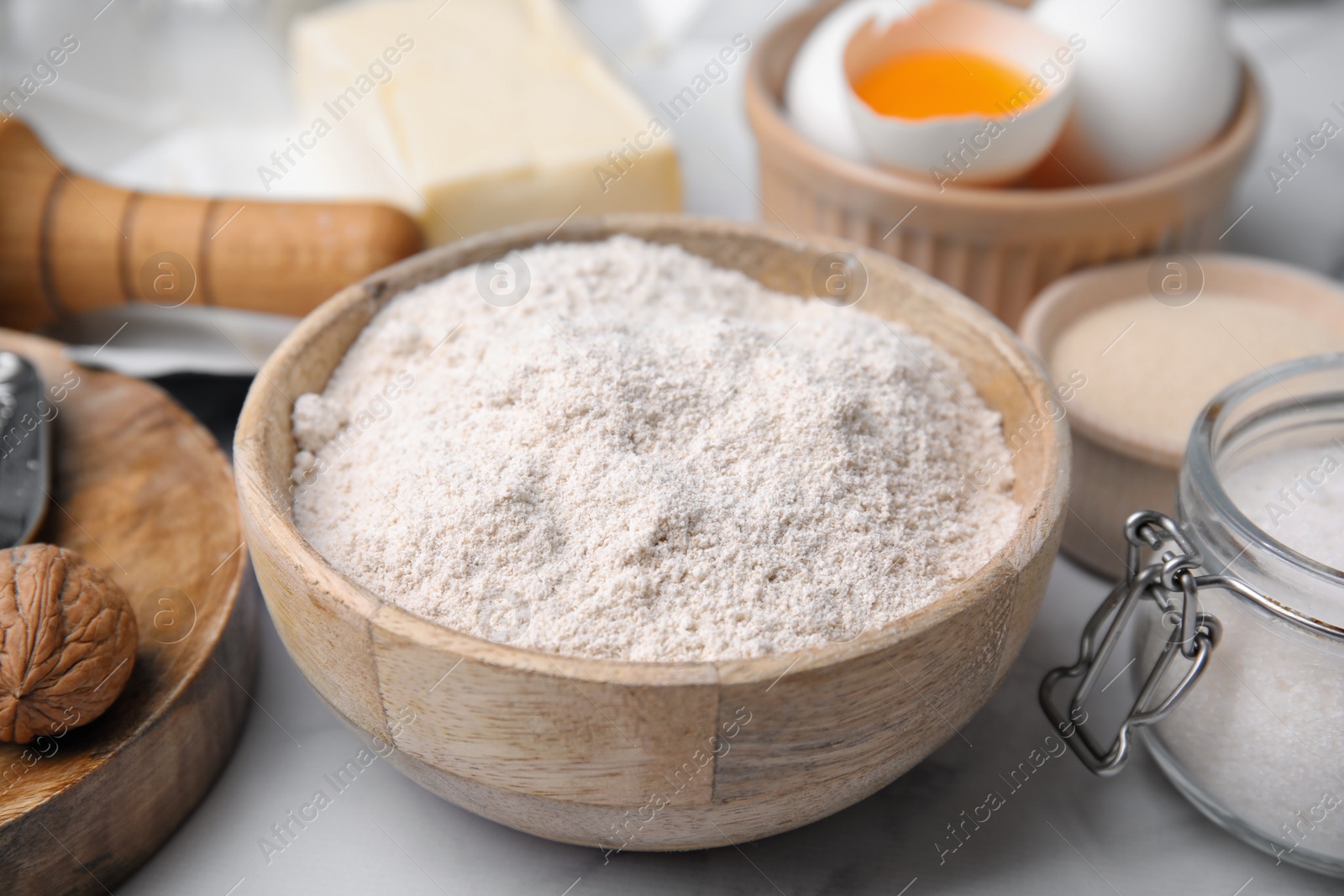 Photo of Bowl of flour and other ingredients on white table, closeup