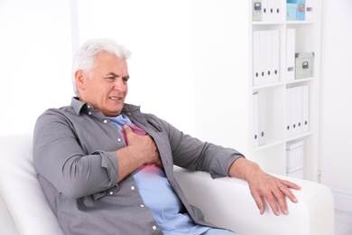 Senior man having heart attack on sofa