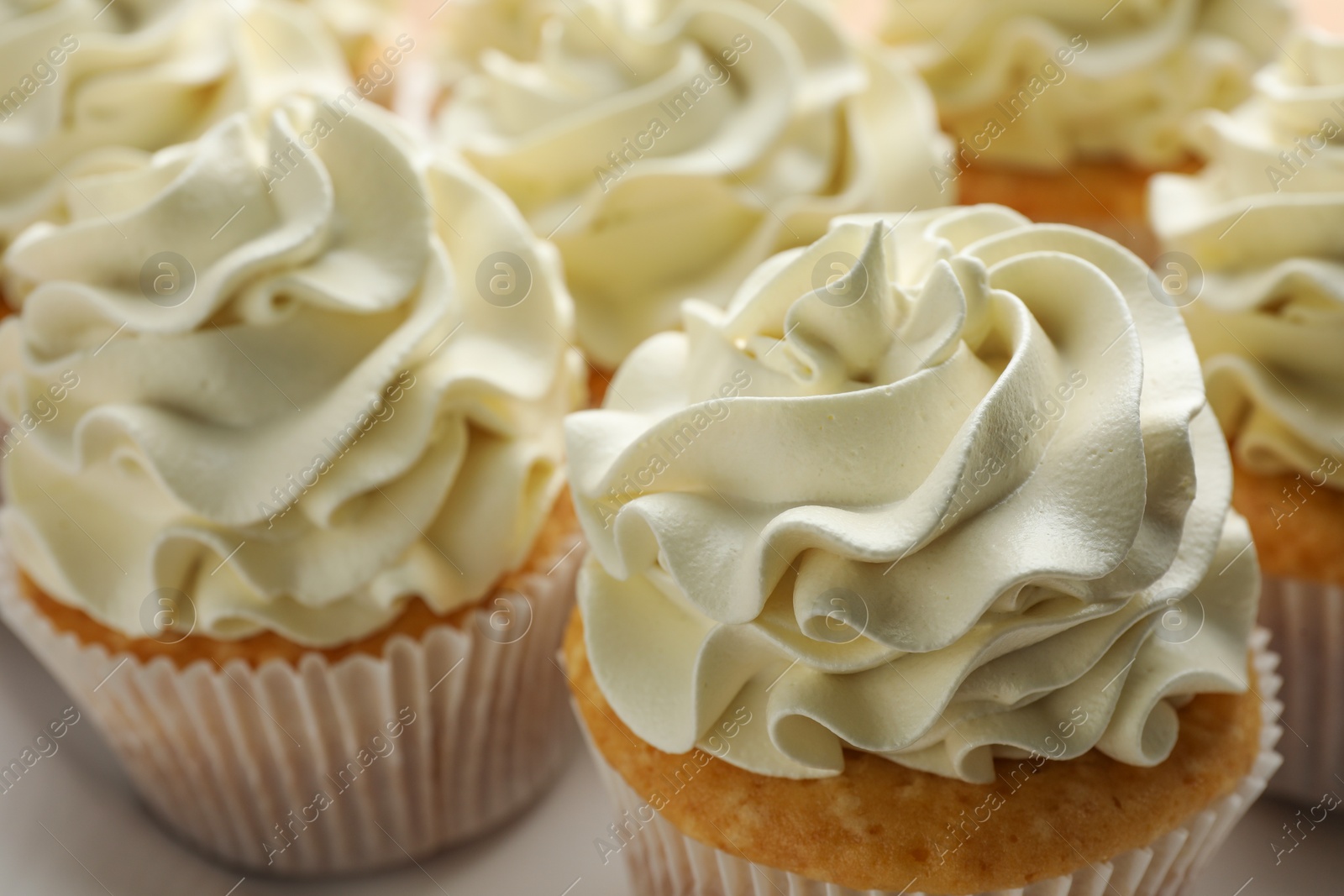 Photo of Tasty vanilla cupcakes with cream on plate, closeup