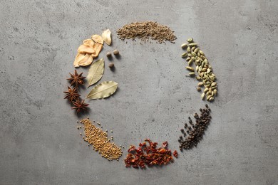 Frame of different spices on grey textured table, flat lay. Space for text
