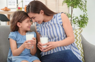 Mother and daughter with glasses of milk in living room