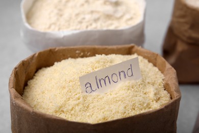 Photo of Sack with almond flour on blurred background, closeup