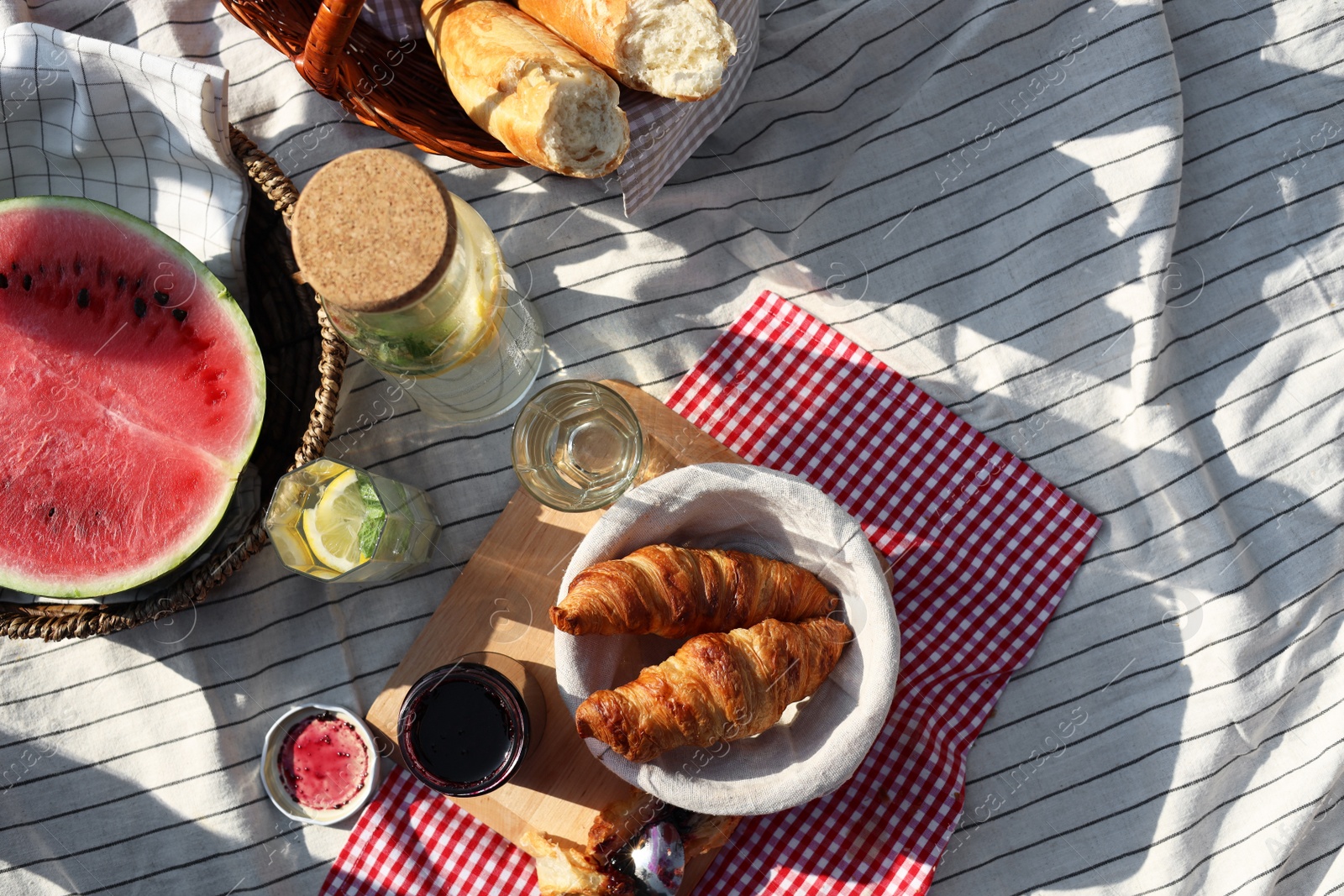 Photo of Delicious food and drink on striped blanket outdoors, flat lay. Picnic season