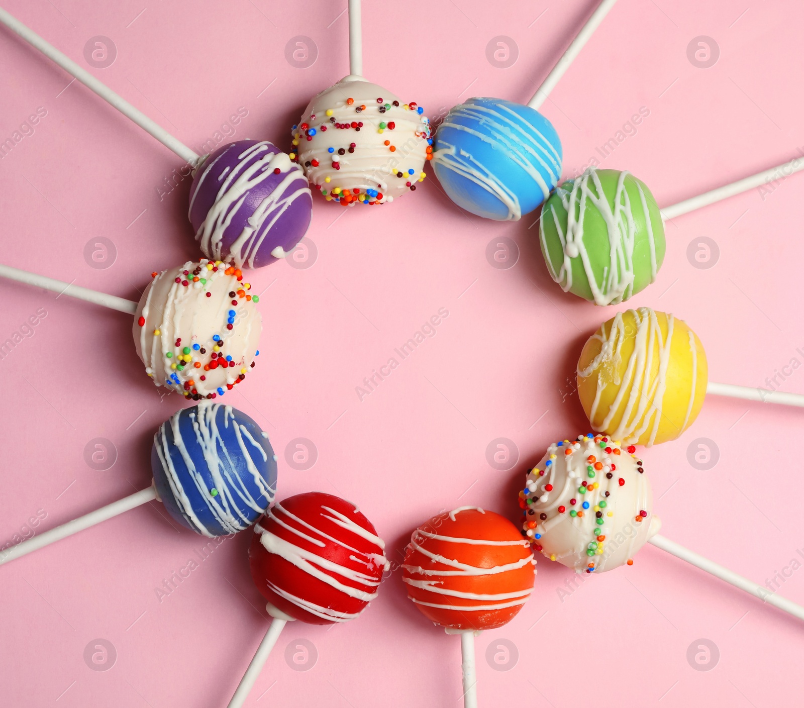 Photo of Frame made of bright delicious cake pops on color background, flat lay. Space for text