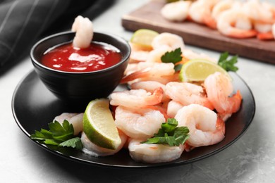 Photo of Tasty boiled shrimps with cocktail sauce, parsley and lime on light grey table