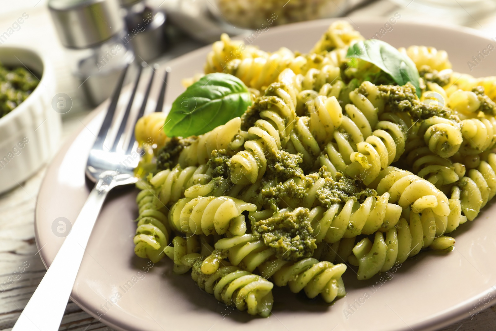 Photo of Plate with delicious basil pesto pasta on table