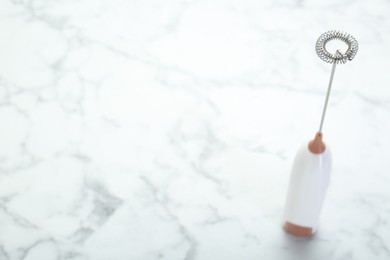 Photo of Milk frother wand on white marble table. Space for text