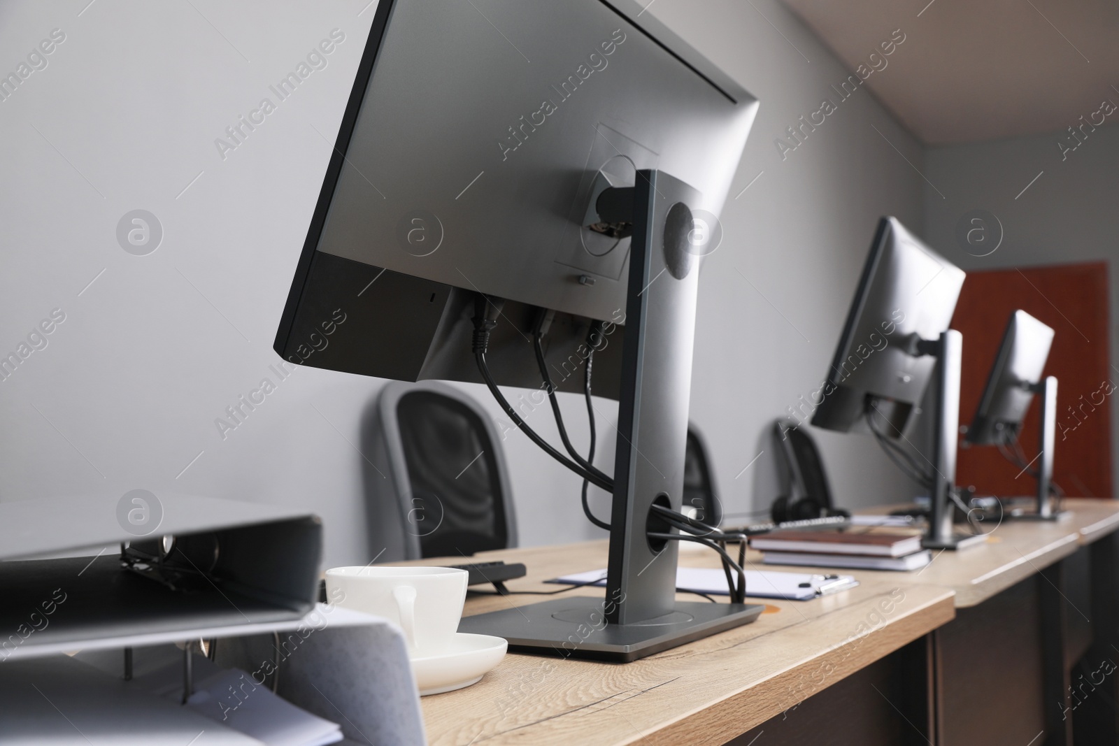 Photo of Open office interior. Modern workplaces with computers near light grey wall