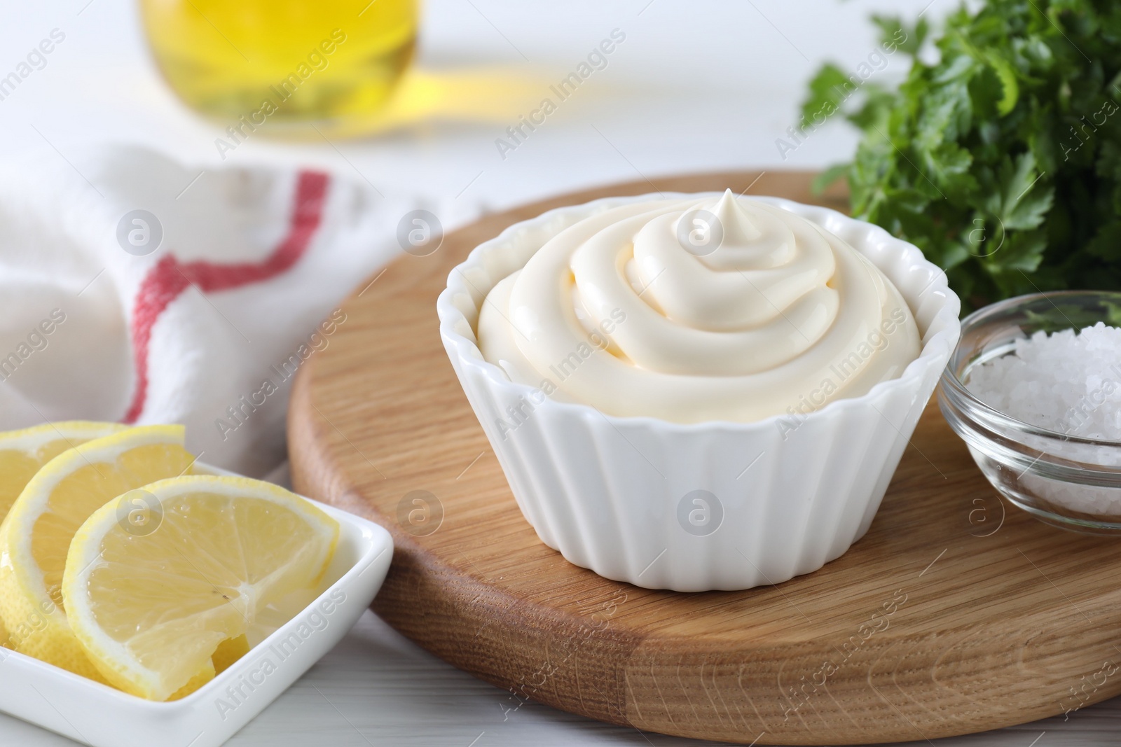 Photo of Fresh mayonnaise sauce in bowl and ingredients on table