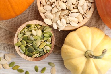 Photo of Bowls with seeds and fresh pumpkins on light wooden table, flat lay