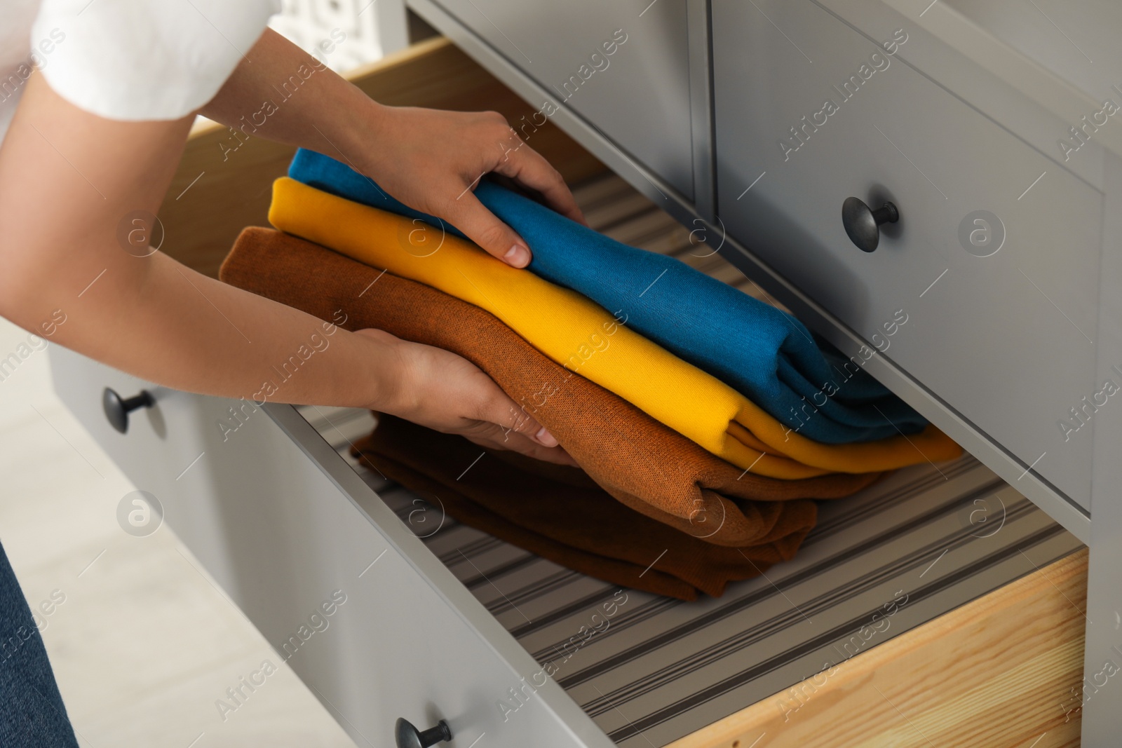 Photo of Woman putting clean clothes into drawer at home, closeup