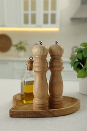 Wooden salt and pepper shakers, bottle of oil on white table in kitchen