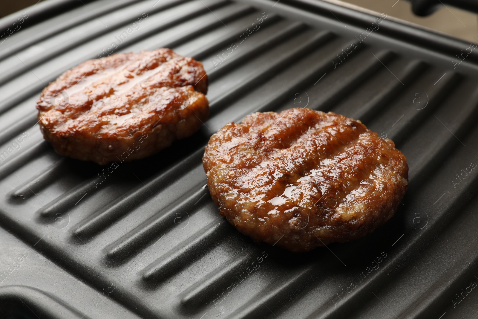 Photo of Delicious hamburger patties on electric grill, closeup