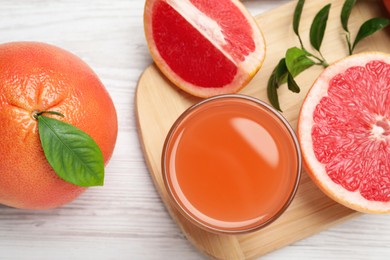 Photo of Tasty freshly made grapefruit juice and fruits on white wooden table, flat lay