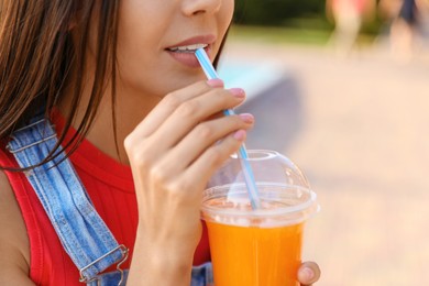 Image of Young woman drinking tasty juice outdoors, closeup