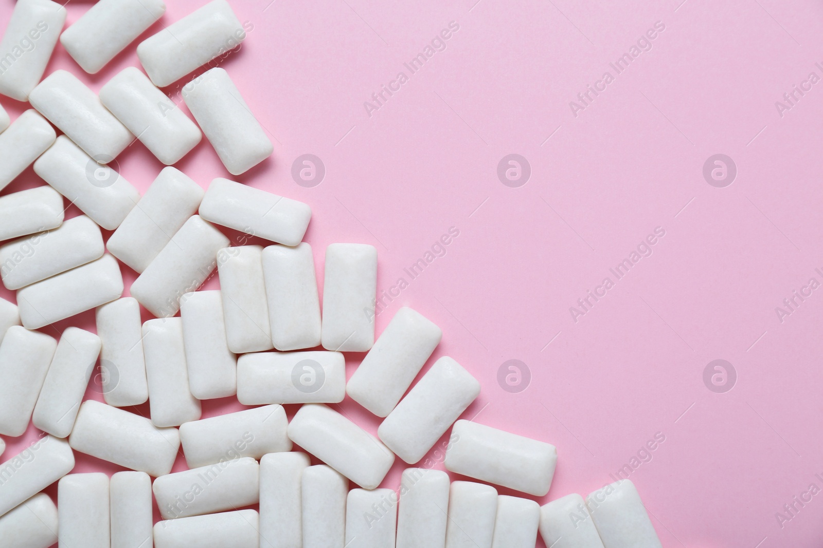 Photo of Tasty white chewing gums on pale pink background, flat lay. Space for text