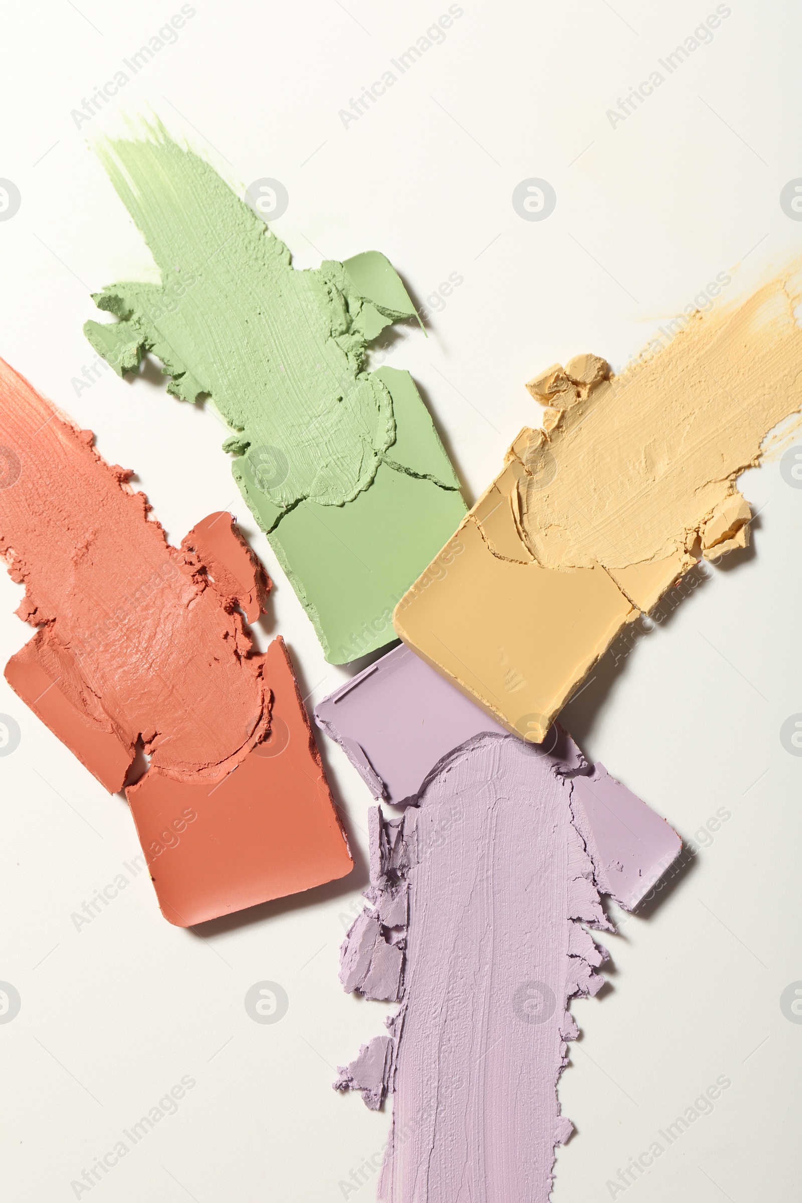 Photo of Samples of different color correcting concealers on white background, top view