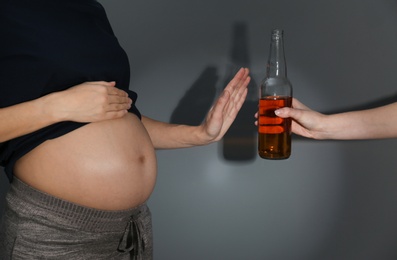 Photo of Pregnant woman declining whiskey on dark background. Alcohol harm